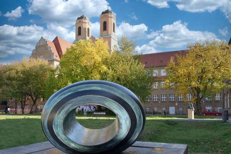 Das Bild zeigt den modernen grafischen Button, der sich spiegelt. Darauf die Worte Bach über Bach, das graue Bach Gemälde von Briana, die Notenlinie mit den Noten B-A-C-H und der FAQ Button als Kreis.