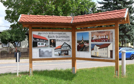 Im Bild im Kapitel Ursprung sieht man einen Touristenhinweis auf einem kleinen Plakat mit einem mit Ziegeln überdachten Konstrukt. Man sieht das Portrait von Bach und den Willkommensgruß.