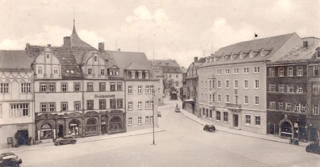Ein Blick auf den Marktplatz von Weimar. Es ist aus der Luft fotografiert, es ist eine historische Postkarte. Unten in der Bildmitte sieht man freie Fläche, einige historische Autos parken.